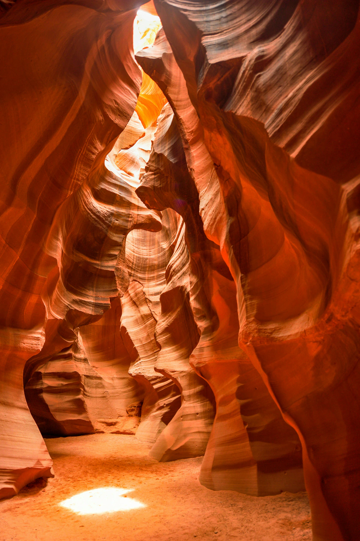 Narrow Antelope Canyon passage with sunlight on the sandy floor