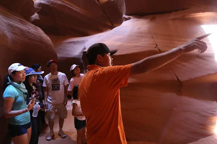 Navajo guide pointing out features to a tour group inside Upper Antelope Canyon