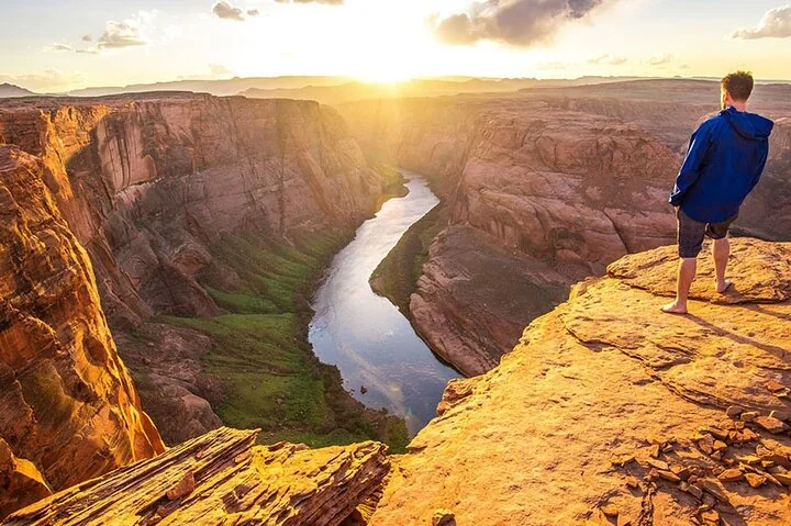 Visitor standing above the Colorado River at Horseshoe Bend